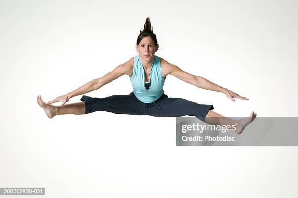 young woman leaping with arms and legs outstretched, posing in studio, portrait - jambes écartées photos et images de collection