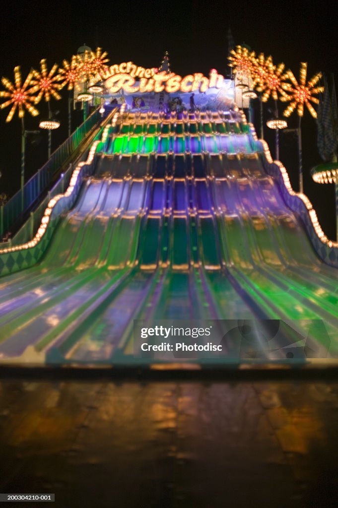 Colourful illumination on fairground slide, at nigh time