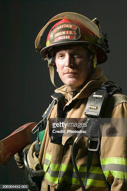 fireman in full uniform holding axe in studio, portrait - fireman axe stock pictures, royalty-free photos & images