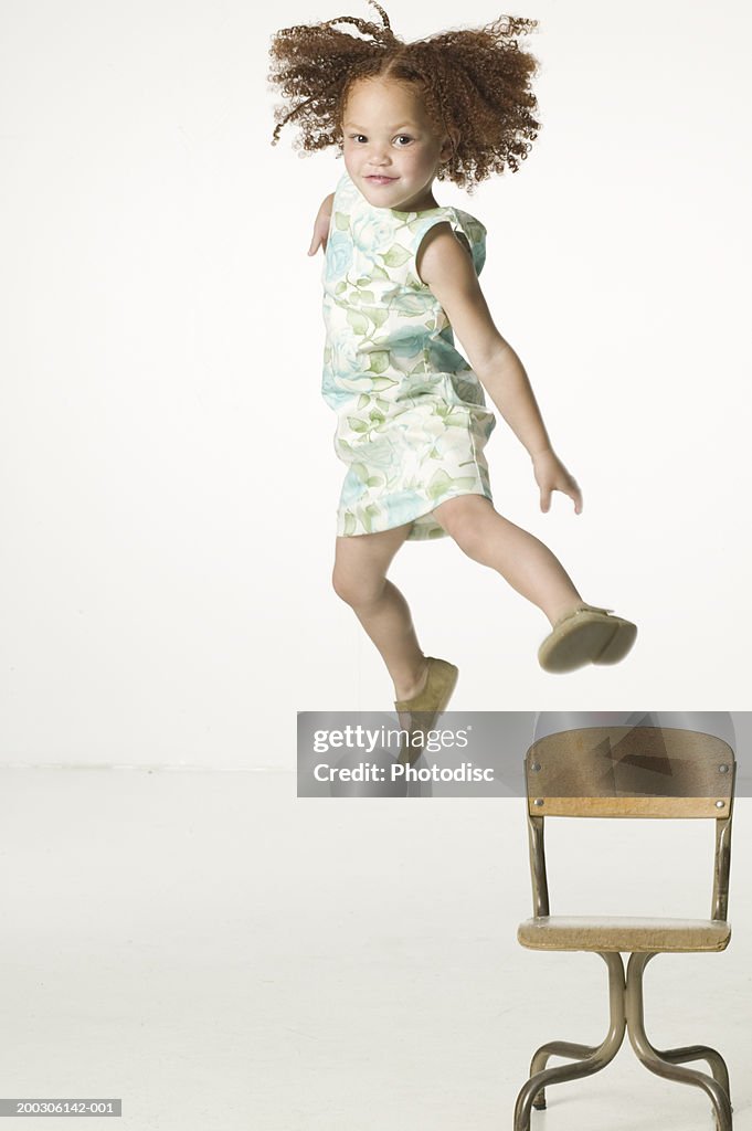 Young girl jumping off chair, portrait