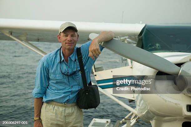 man standing by seaplane with arm on propeller - seaplane stock pictures, royalty-free photos & images