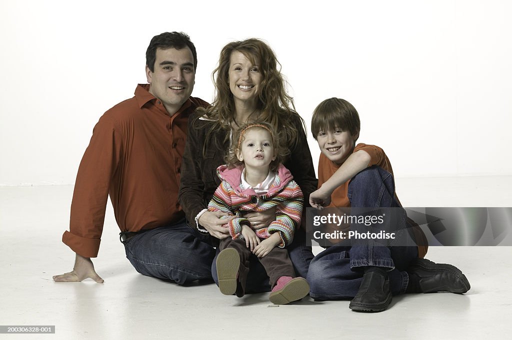 Family sitting on floor, posing, son (8-9) daughter (3-4), portrait