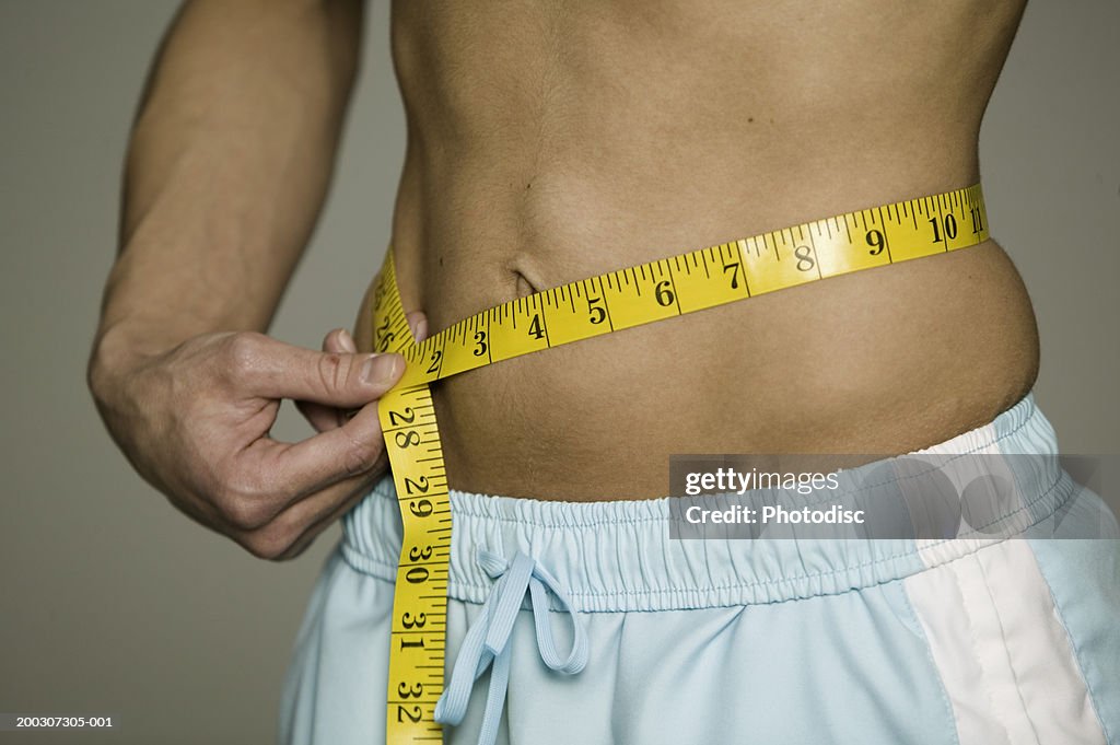 Man measuring waist , mid section