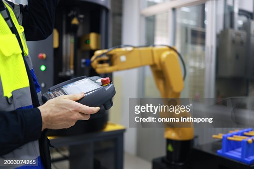 Technician using remote controller control inspection robot arm welding machine in the factory. Team of technician automation robot system.