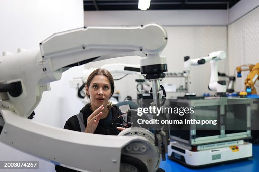 Factory Female Industrial Engineer working with automation robot arms machine in intelligent factory industrial on real-time monitoring system software.Digital future manufacture. Factory Female Industrial Engineer working with automation robot arms machine in intelligent factory industrial on real-time monitoring system software.Digital future manufacture.