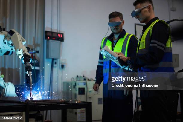 two male engineers using vr glasses to control the robotic welding arm in the factory production line. - wearable technology or smart technology or innovative technology or new technology or techn stock pictures, royalty-free photos & images