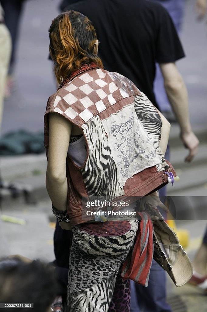 Young punk standing on street, rear view