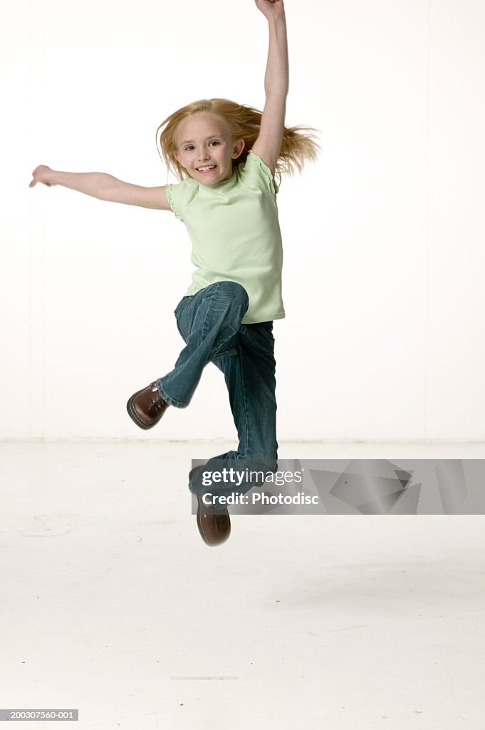 Girl (5-6) jumping in studio