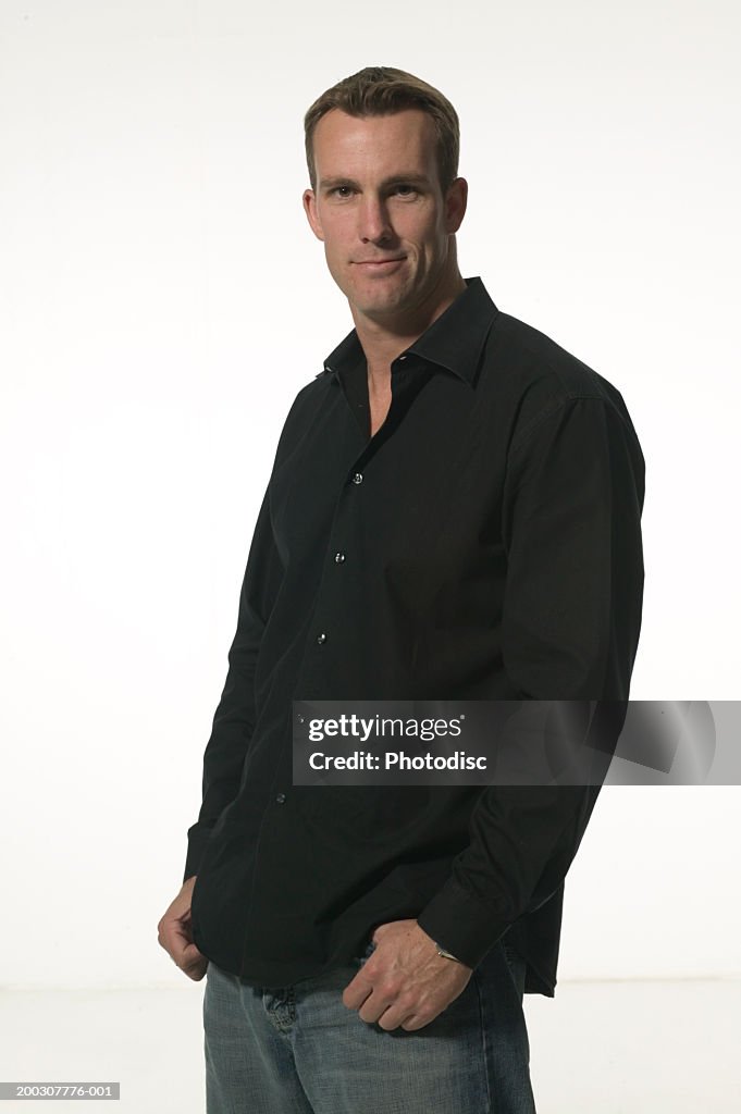 Man standing indoors with hands in pockets, posing, portrait