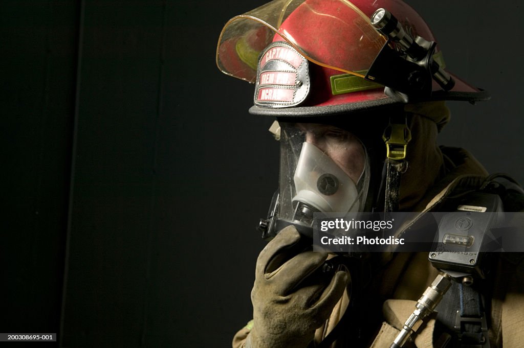 Fire fighter standing in uniform wearing face mask