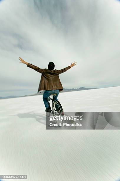 man riding bicycle hands free, in desert, elevated view - hands free cycling stock pictures, royalty-free photos & images