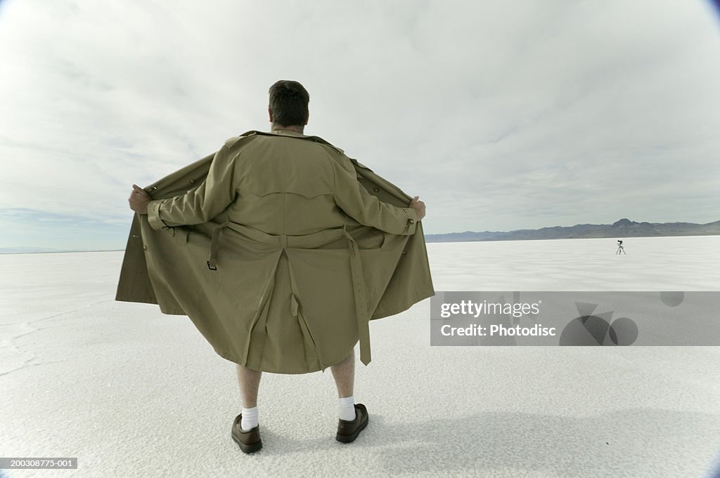 Exhibitionist spreading open coat in desert