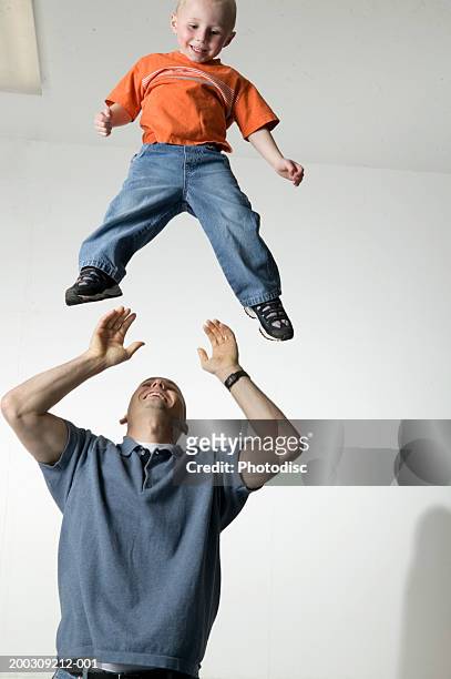man throwing boy (6-7), in air in studio, portrait - dad throwing kid in air stockfoto's en -beelden