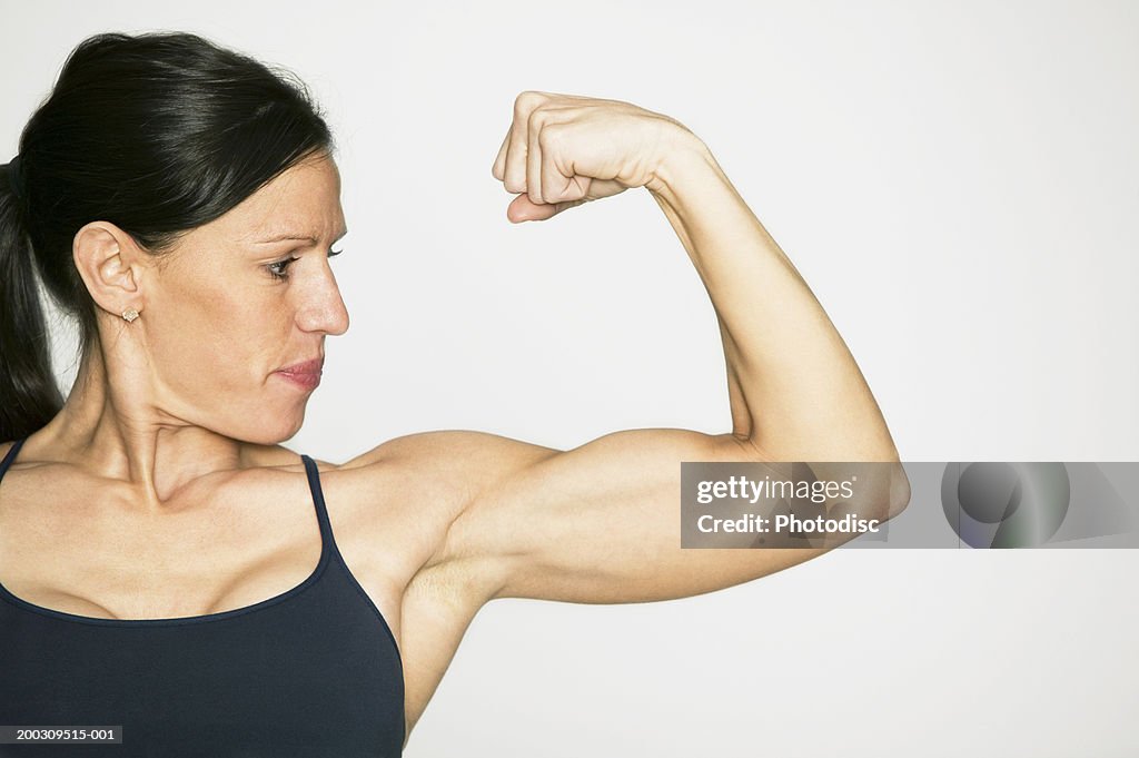 Young woman flexing muscles in studio, portrait