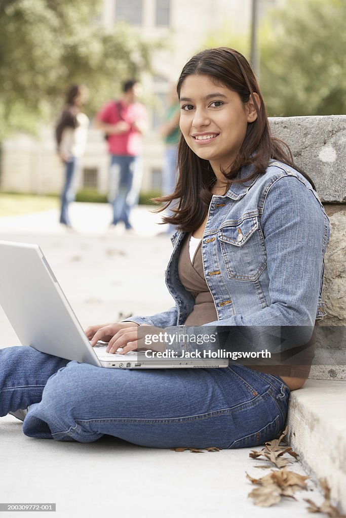 Portrait of a young woman sitting on the floor with a laptop