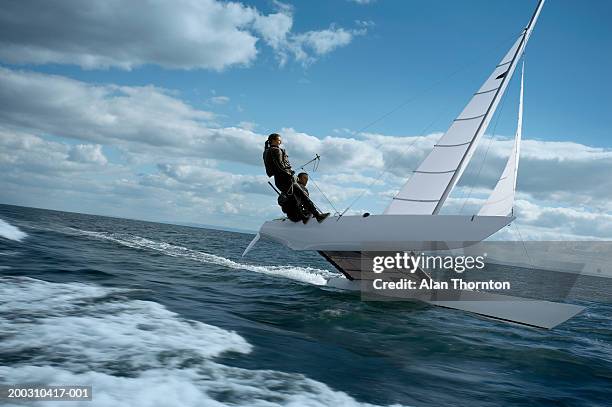 couple sailing catamaran - katamaran segeln stock-fotos und bilder