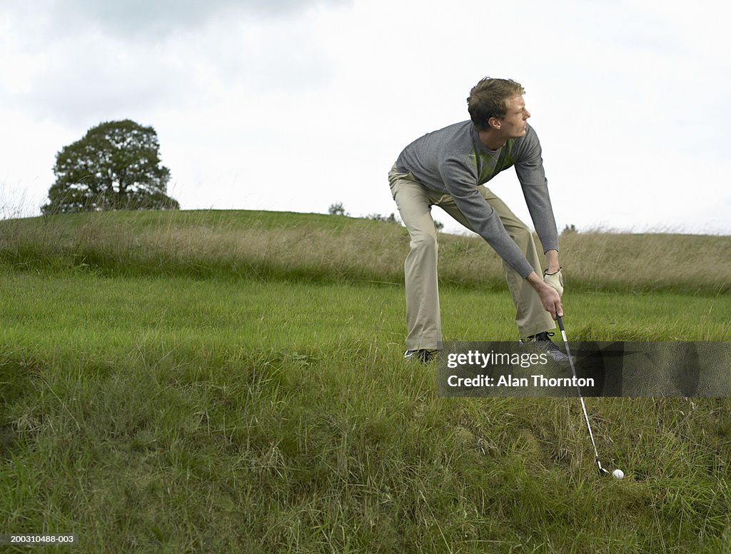 Male golfer preparing to hit ball out of ditch