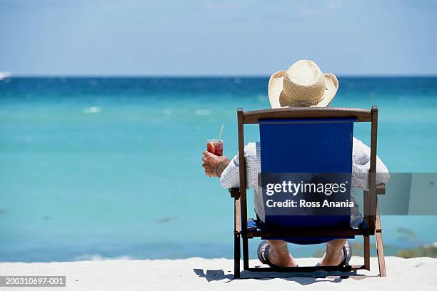 usa, florida, miami beach, man in beach chair with drink, rear view - strohhut stock-fotos und bilder