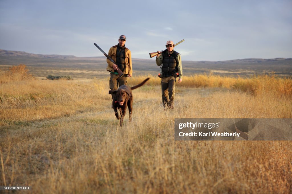 Two men hunting with Chocolate labrador, portrait