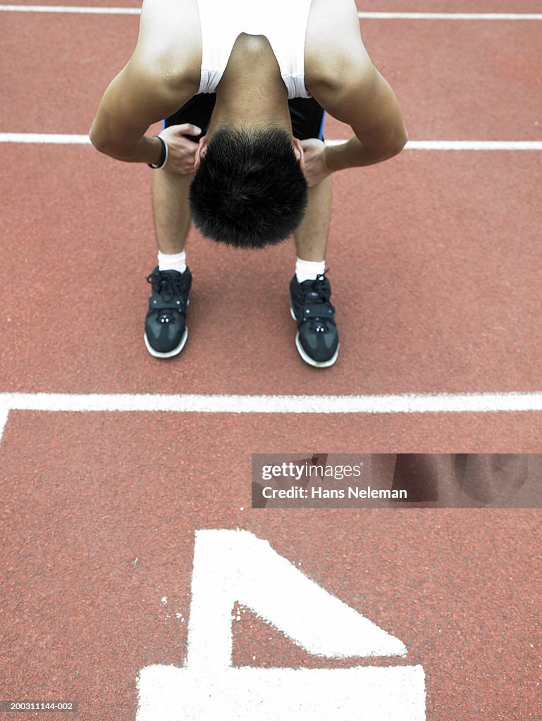 Teenage male runner (17-19) bending over after race, elevated view