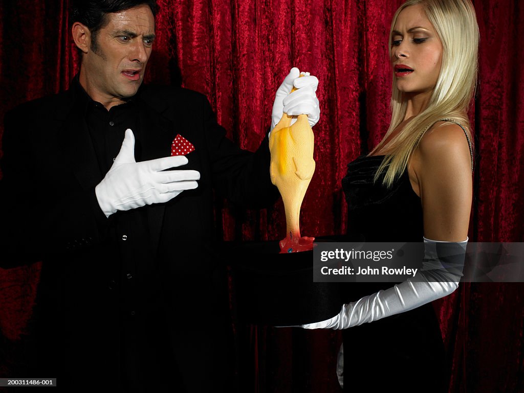 Magician and female assistant performing magic trick, frowning