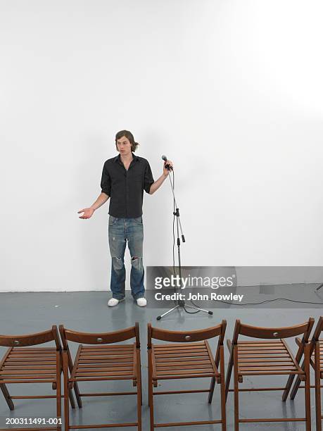 man standing by microphone facing empty chairs - microphone stand - fotografias e filmes do acervo