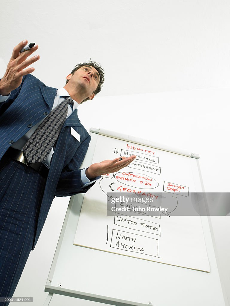 Businessman giving presentation holding out hands, low angle view