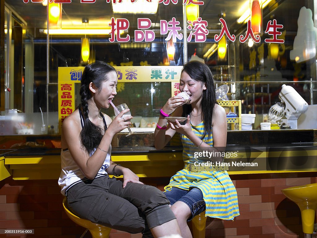 Young woman and teenage girl (17-19) having snacks at cafe