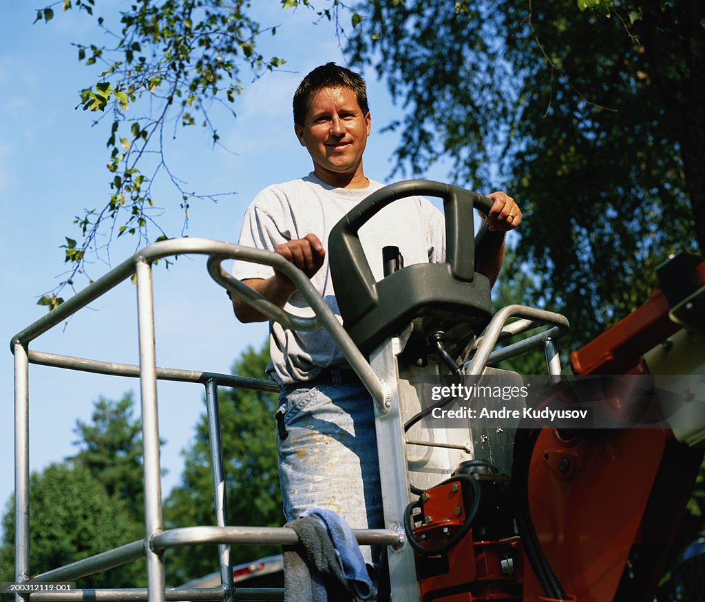 Man at controls of cherry picker, smiling, portrait