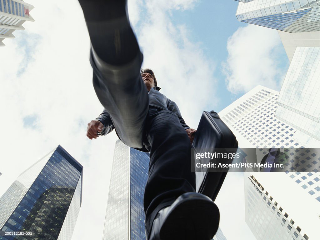 Casually dressed mature businessman walking in city, view from below