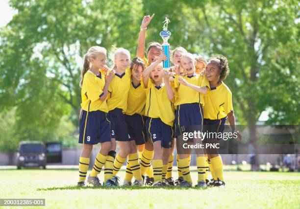 girls (10-17) in soccer uniforms holding trophy on field, cheering - soccer team stock pictures, royalty-free photos & images