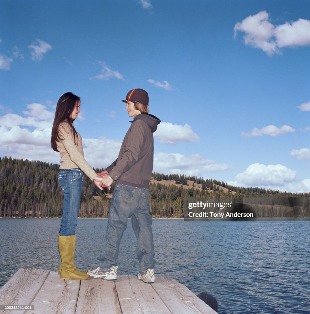 Teenage couple (14-16) holding hands on dock, side view