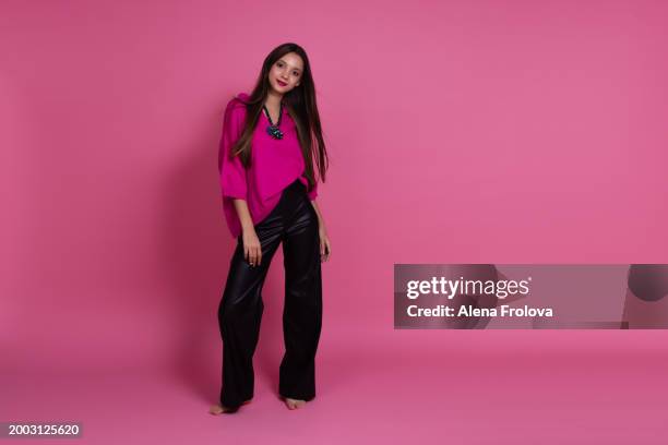 beautiful girl standing and smiling and dressing magenta jumper, leather trousers  pink background springtime - teen boots russian stock pictures, royalty-free photos & images