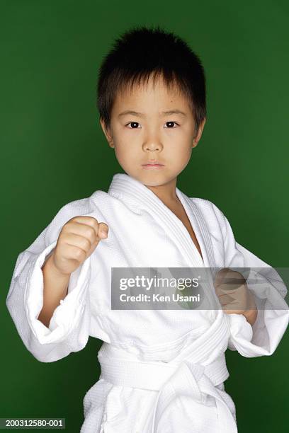 boy (5-7) wearing karate uniform in karate pose, portrait - karateka photos et images de collection