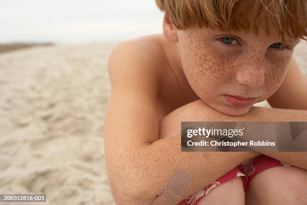 boy (6-8) sitting on beach, leaning on knees, close-up, portrait - boy freckle stock pictures, royalty-free photos & images