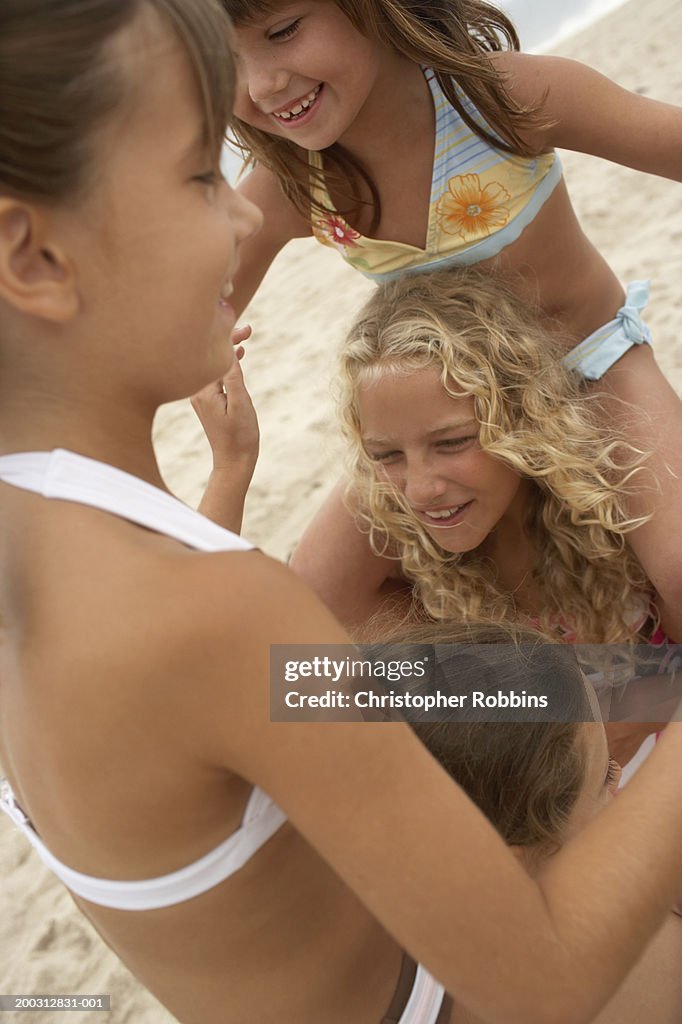 Four girls (6-12) playing on beach, laughing, close-up