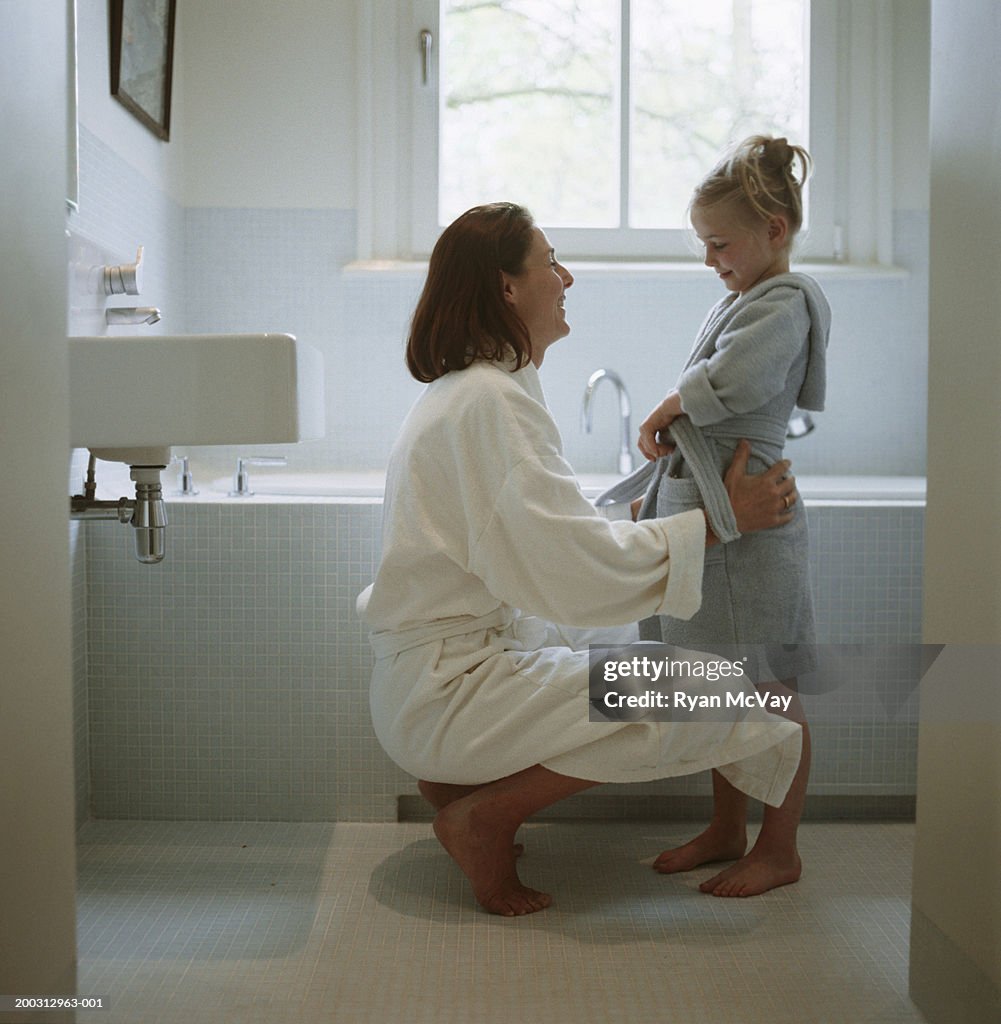 Mother and daughter (2-3) wearing dressing gowns in bathroom