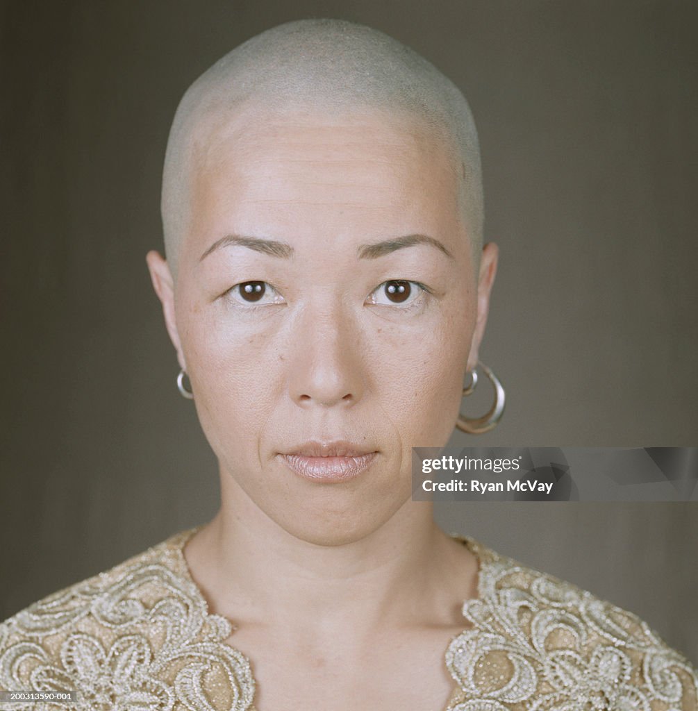 Woman with bald head and earrings, posing in studio, portrait