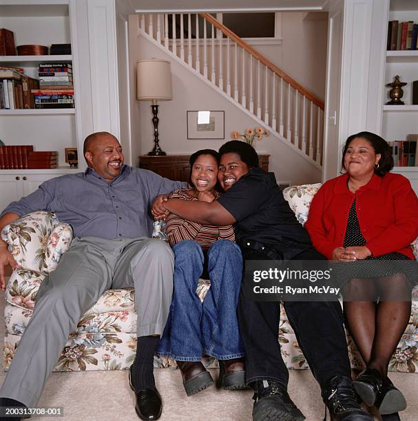 two parents with teenage son and daughter (16-17), sitting on sofa in living room, portrait - chubby teenager ストックフォトと画像