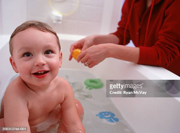 boy (4-5) sitting in bathtub, mother at bath side, - woman bath tub wet hair stock pictures, royalty-free photos & images