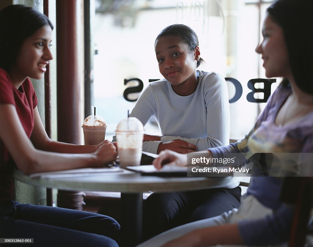 Three teenage girls (16-17) sitting in cafe