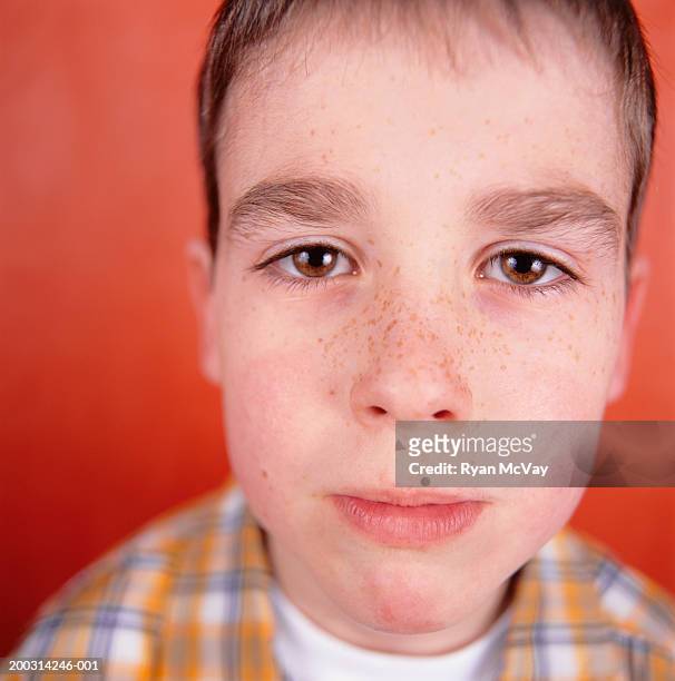 boy (8-9), with freckles, posing in studio, close-up, portrait - buschig stock-fotos und bilder