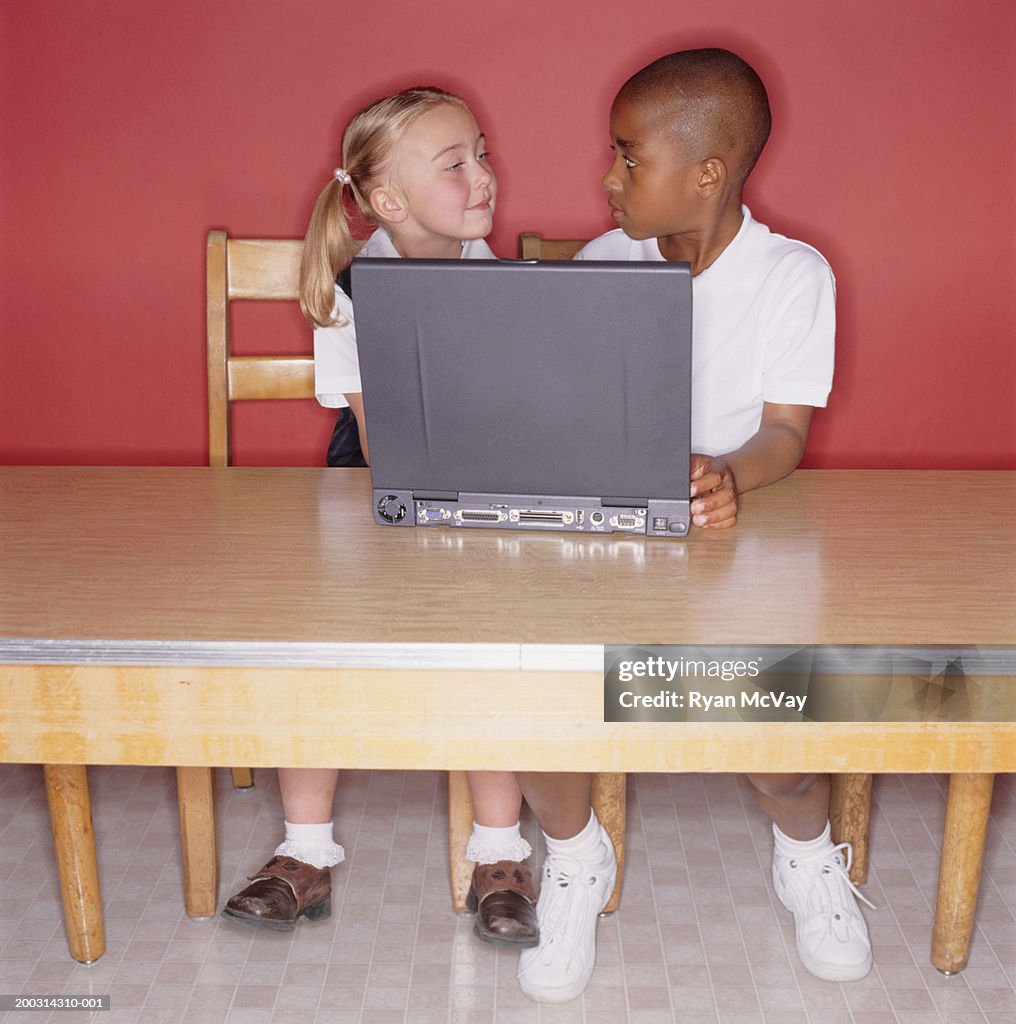 Boy and girl (8-9) using laptop, posing in studio, portrait