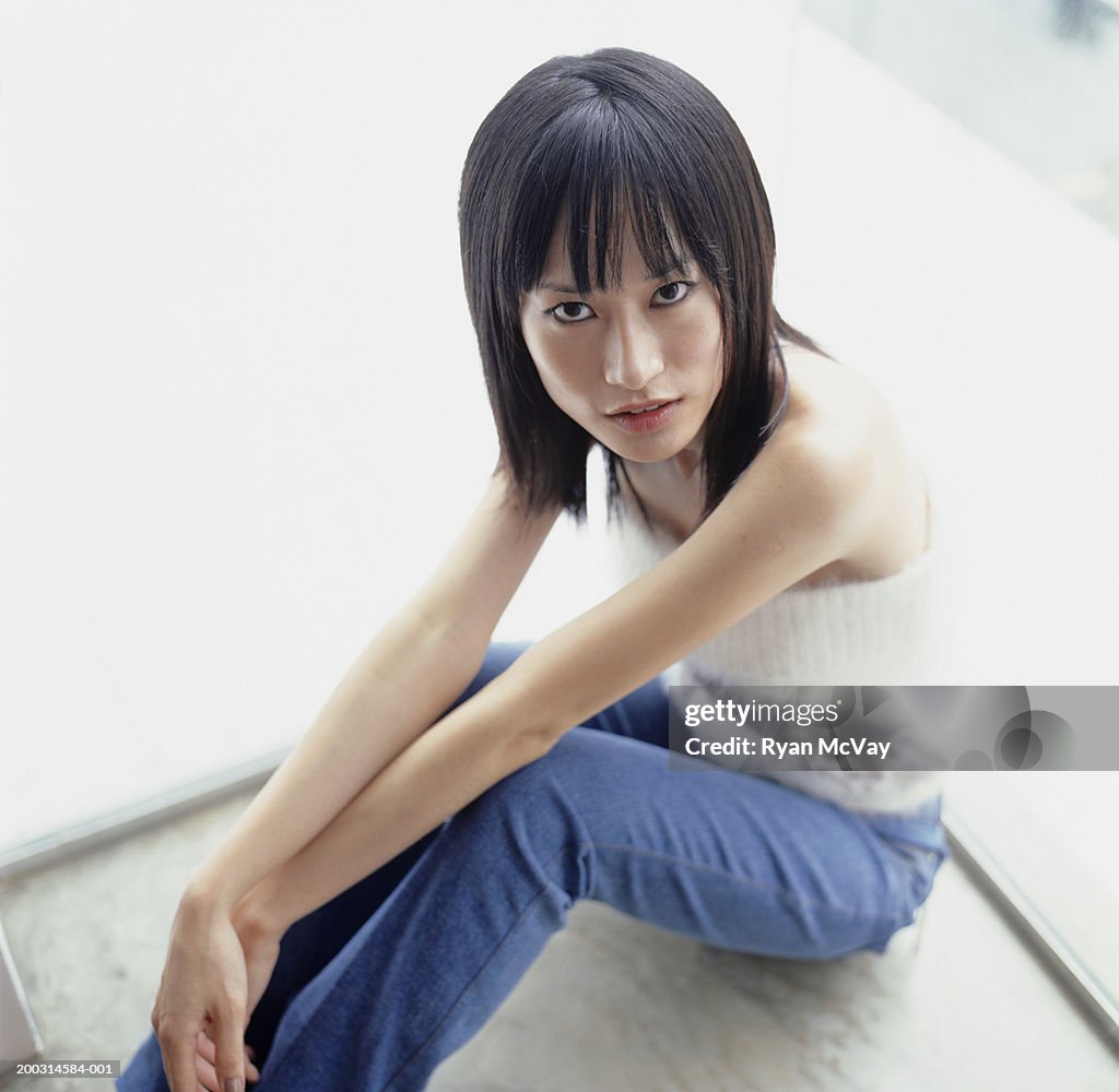 Young woman sitting on floor indoors, elevated view