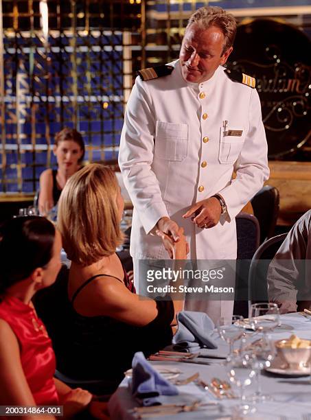 captain greeting two woman  in cruise ship restaurant - ship captain stock pictures, royalty-free photos & images