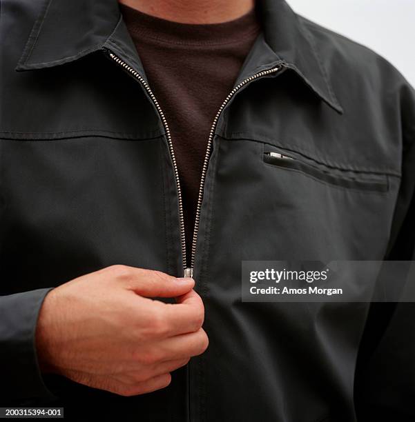 man unzipping jacket, posing in studio, mid section, close-up - rits stockfoto's en -beelden