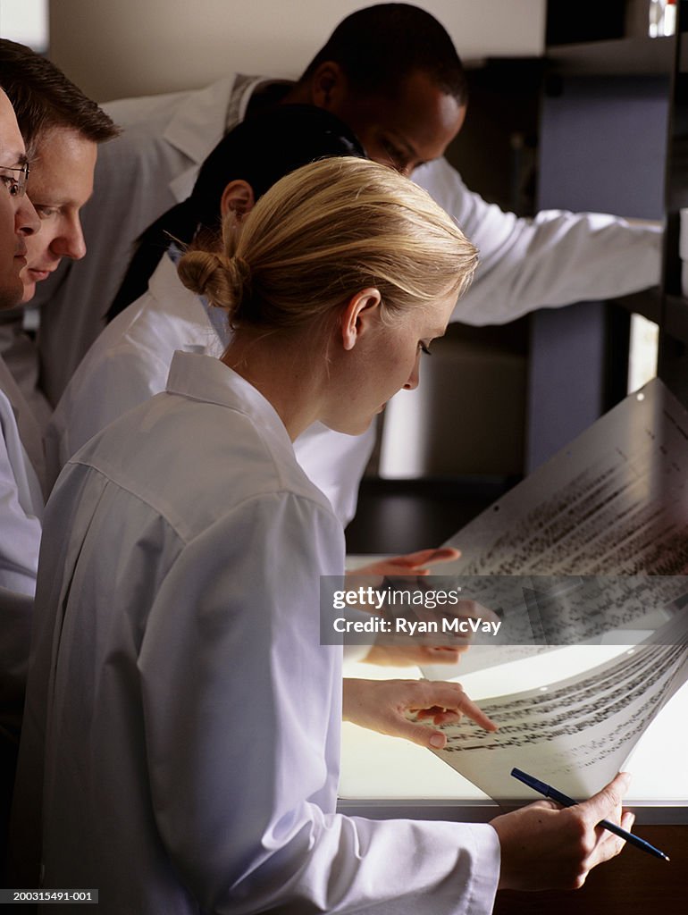 Five scientists checking results on graph in laboratory