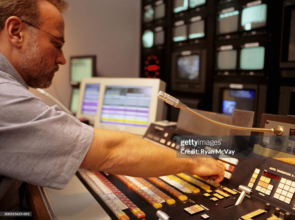 Mature man working at mixing console in television studio
