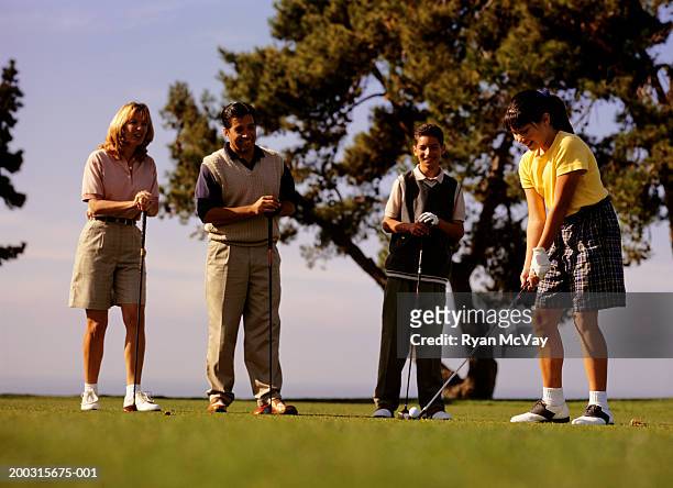 family with two children (12-13), (16-17), on golf course - golf girls stock-fotos und bilder