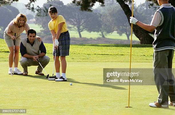 family with two children (12-13), (16-17), on putting green at golf course - mother with daughters 12 16 stock-fotos und bilder